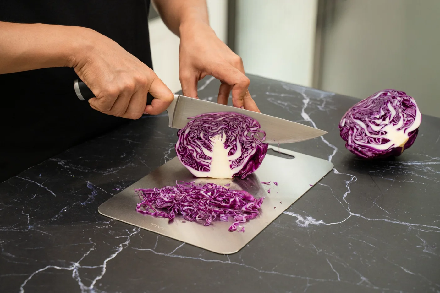 Purple cabbage being sliced on Tivano Cutting Board