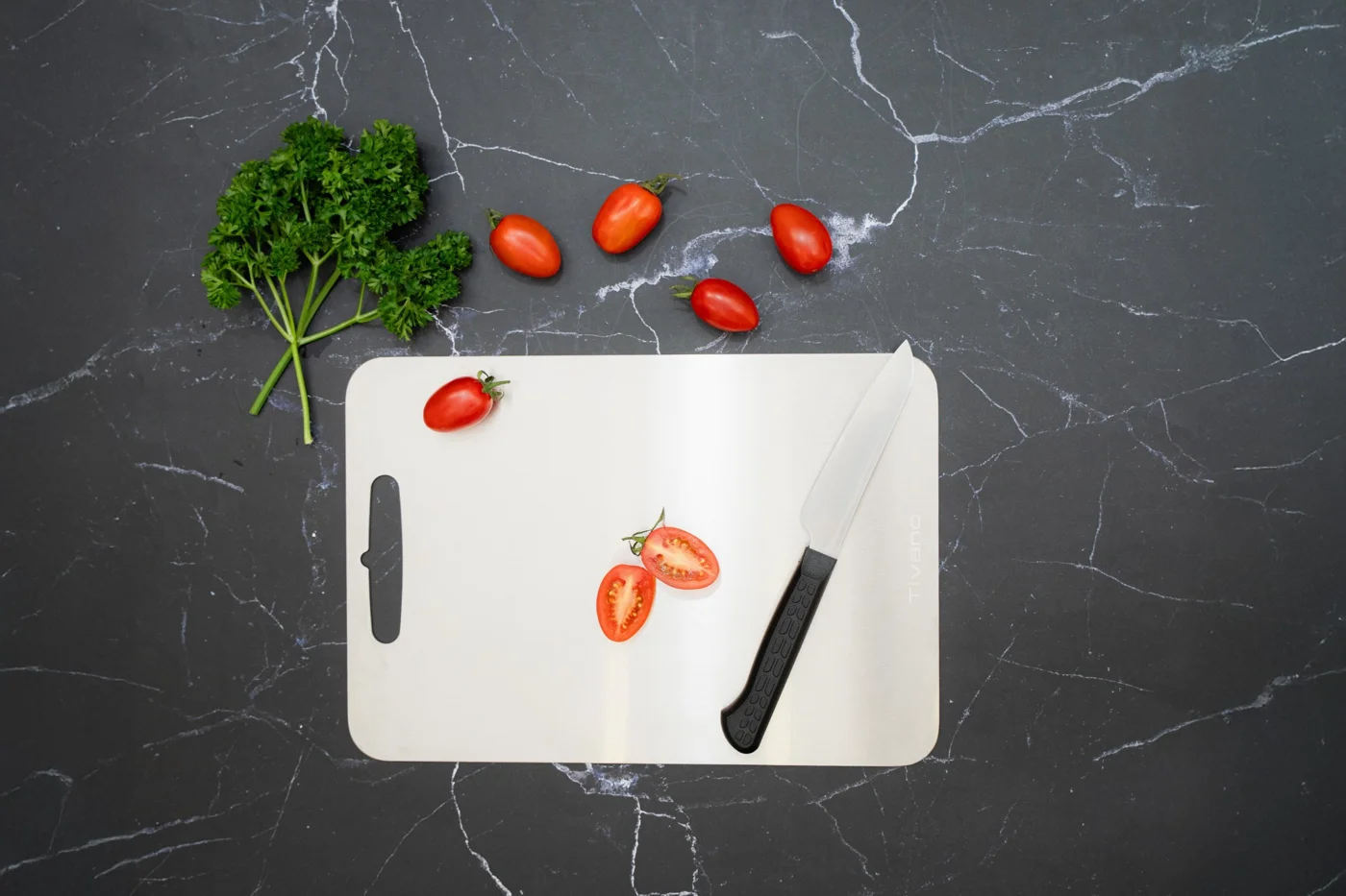 Tivano Cutting Board photographed from above with tomatoes and a kitchen knife